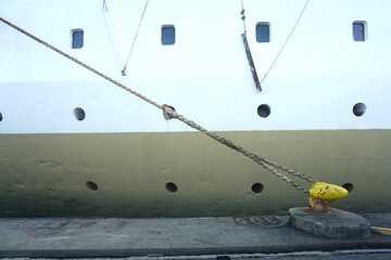 Thick rope secures massive ship to dockside bollard in maritime scene
