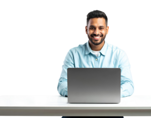 An attractive Indian man smiling and using a laptop on a white table, isolated on transparent background.