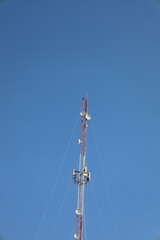 A telecommunication mast with its antenna stands against a clear blue sky, a symbol of global...