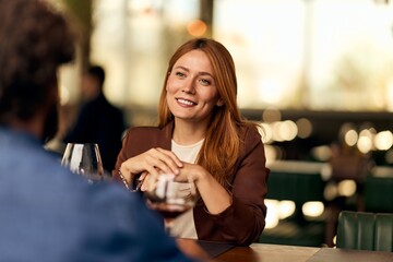Young Woman Enjoying Conversation Over Drinks at a Cozy Restaurant