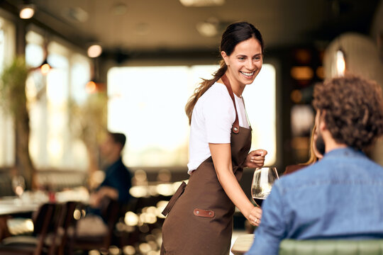 Smiling Waitress Serving Customers in a Cozy Modern Restaurant Interior