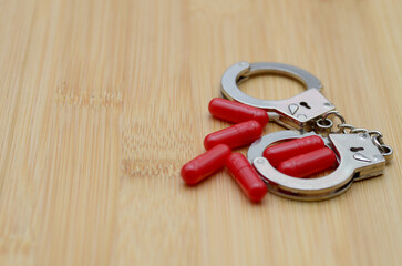Red Pills Inside Handcuffs Represent Drug Arrest and Legal Consequences