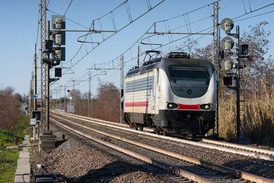 Locomotiva isolata oltrepassa segnali ferroviari lungo linea ferroviaria a due binari