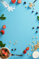 A frame with cereal, milk, strawberries, blueberries, and mint on a blue background. Space for your text or design.