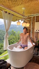 Handsome Man Relaxing in Bubble Bath on Veranda Amidst Lush Green Forest and Gentle Rain