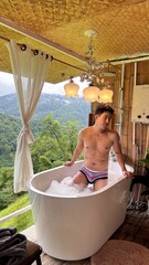 Handsome Man Relaxing in Bubble Bath on Veranda Amidst Lush Green Forest and Gentle Rain