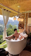 Handsome Man Relaxing in Bubble Bath on Veranda Amidst Lush Green Forest and Gentle Rain