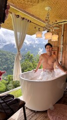 Handsome Man Relaxing in Bubble Bath on Veranda Amidst Lush Green Forest and Gentle Rain