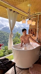 Handsome Man Relaxing in Bubble Bath on Veranda Amidst Lush Green Forest and Gentle Rain