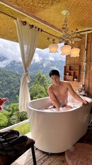 Handsome Man Relaxing in Bubble Bath on Veranda Amidst Lush Green Forest and Gentle Rain