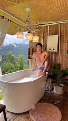 Handsome Man Relaxing in Bubble Bath on Veranda Amidst Lush Green Forest and Gentle Rain