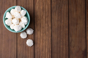 Fresh homemade meringue cookies over wooden background with copy space