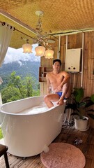 Handsome Man Relaxing in Bubble Bath on Veranda Amidst Lush Green Forest and Gentle Rain