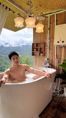Handsome Man Relaxing in Bubble Bath on Veranda Amidst Lush Green Forest and Gentle Rain