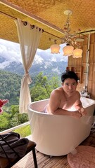 Handsome Man Relaxing in Bubble Bath on Veranda Amidst Lush Green Forest and Gentle Rain