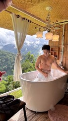 Handsome Man Relaxing in Bubble Bath on Veranda Amidst Lush Green Forest and Gentle Rain