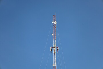 A telecommunication mast with its antenna stands against a clear blue sky, a symbol of global wireless communication technology