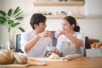 Happy couple preparing homemade cookies together in a cozy kitchen, enjoying the baking process.