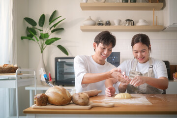 Smiling couple preparing cookie dough together in a cozy kitchen, enjoying homemade baking.