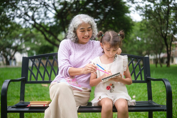 Senior woman and young girl bonding through creative drawing on a sunny day at the park.