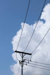 High-voltage power lines crisscross the blue sky, supported by massive industrial pylons and towers...
