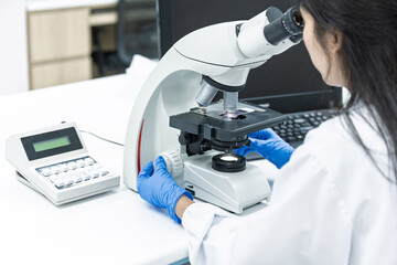Asian women scientist looking to microscope eyepiece from CBC hematology slide in clinical laboratory.Medical technician analysis blood slide on exam plate microscopic at laboratory department.