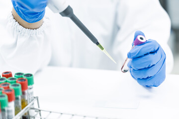 Scientist hand holding pipette drop blood from blood test tube.Health care researchers working in life science laboratory research work for test a vaccine and pharmacy production of medicines test.