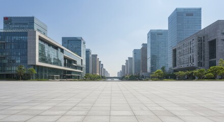 Wide paved plaza between modern glass office buildings under a clear blue sky.