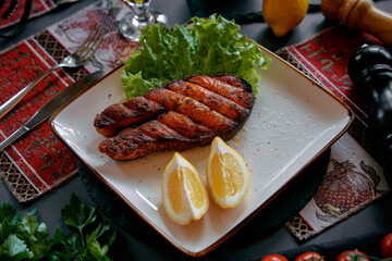 A Deliciously Grilled Salmon Steak Served with Fresh Lettuce and Lemon Garnish, Perfectly Arranged on a Decorative Plate for a Culinary Delight