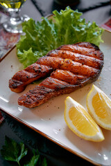 Grilled Salmon Steak Served with Fresh Green Lettuce and Lemon Wedges for a Delicious and Healthy Meal Option