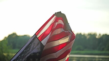 Slow motion shot of woman lifting American flag into sky at golden sunset - Powered by Adobe