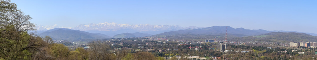 Panorama of the city with a view of the snow-capped peaks of the mountains in summer. A landscape with views of the mountains and city streets in summer. The city of Nalchik in Kabardino-Balkaria.