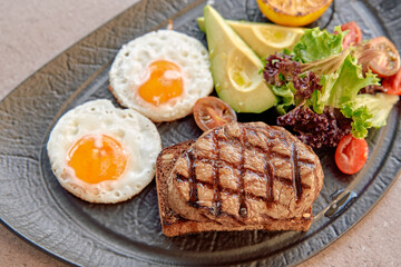A Delicious Plate Featuring Grilled Steak, Fried Eggs, Fresh Vegetables, and Sliced Fruits Artfully Presented for a Balanced Meal