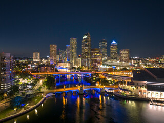 Obraz premium American city skyline of Tampa in Florida. Brightly illuminated commercial buildings and highway bridge over Hillsborough river. Night urban landscape of downtown district in USA.