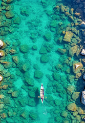 透明な水面を進むカヌー。上空から見た自然の旅路