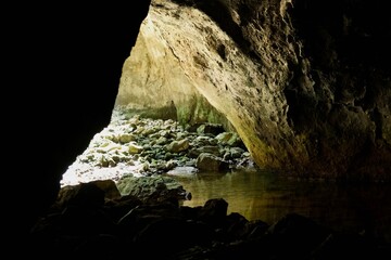 View from the inside of a water cave with a rocky entrance and reflected light, &Scaron;kocjanski Zatok, Slovenia