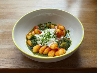 Potato gnocchi with pesto, sour cream, and chives. Modern Italian cuisine concept. Handheld mobile photo, selective focus, non AI