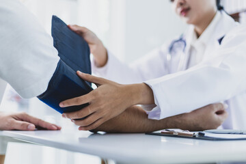 Obraz premium Female doctor measuring blood pressure of patient in hospital room. Doctor using sphygmomanometer checking blood pressure of patient during medical exam in clinic, healthcare and medical concept.
