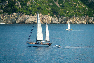 Two sailing boats sailing in the open sea near an island