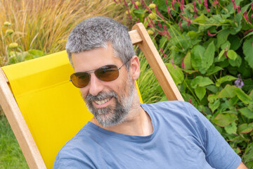 Mature man with silver beard, sunglasses enjoying leisure moment an smiling with a relaxed...