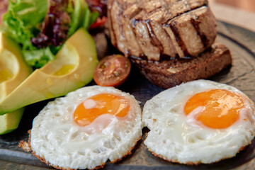 A Delicious Breakfast Plate Featuring Perfectly Cooked Eggs, Grilled Meat, Fresh Vegetables, and Toasted Bread for a Nutritious Start to the Day