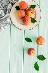 Summer lunch. Red peaches on green wooden background with tablecloth and leaves top-down copy space