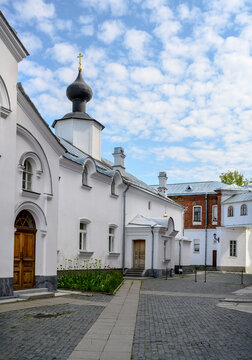 A courtyard with a paved pavement and a refectory with a dome and a cross of the Valaam Monastery on the island of Valaam in Karelia