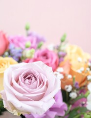 Fototapeta premium A vibrant vase brimming with a variety of colorful flowers, including roses and daisies, sits elegantly atop a rustic wooden table, enhancing the room's charm.
