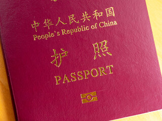 A close-up view of the cover of a dark red passport from the People's Republic of China, featuring the national emblem and "护照 PASSPORT" in golden text.