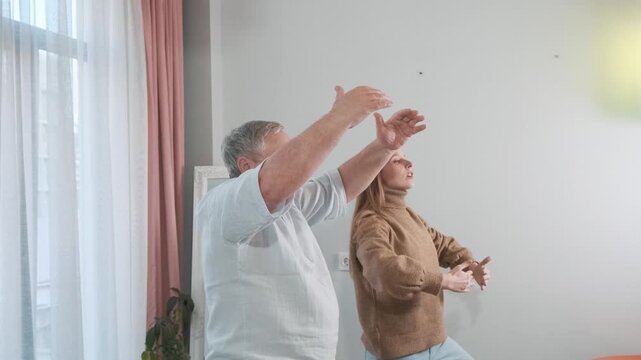 Adult daughter teaching her elderly father balancing on one leg in a yoga pose. Senior fitness, balance training, family exercise, intergenerational wellness, importance of movement for healthy aging