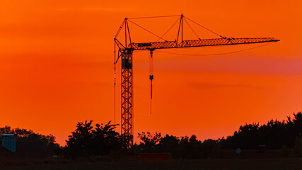 Naklejka premium Summer sunset or sundowner view with a dramatic sky and a construction crane silhouette near Moos, Deggendorf, Bavaria, Germany