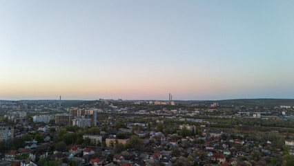 Aerial view of city landscape with buildings and industrial chimneys at dawn dusk
