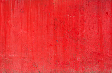Red painted concrete wall showing signs of ageing and wear, creating textured background