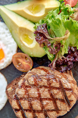 A Delicious Plate Featuring Grilled Steak Accompanied by Fresh Vegetables, Sliced Avocado, and a Poached Egg for a Nutritious Meal Experience